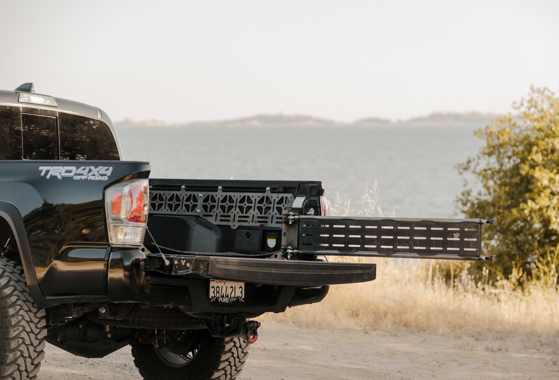 a black truck parked on a dirt road next to a body of water