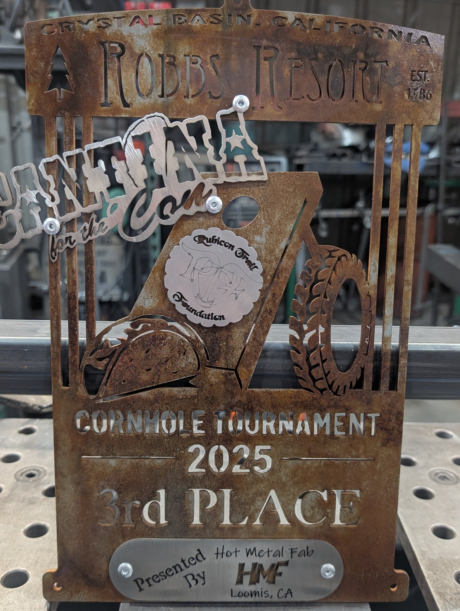 Rust-colored metal trophy with engraved text and design on a metal surface.