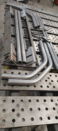 Load image into Gallery viewer, a bunch of metal pipes are lined up on a rack
