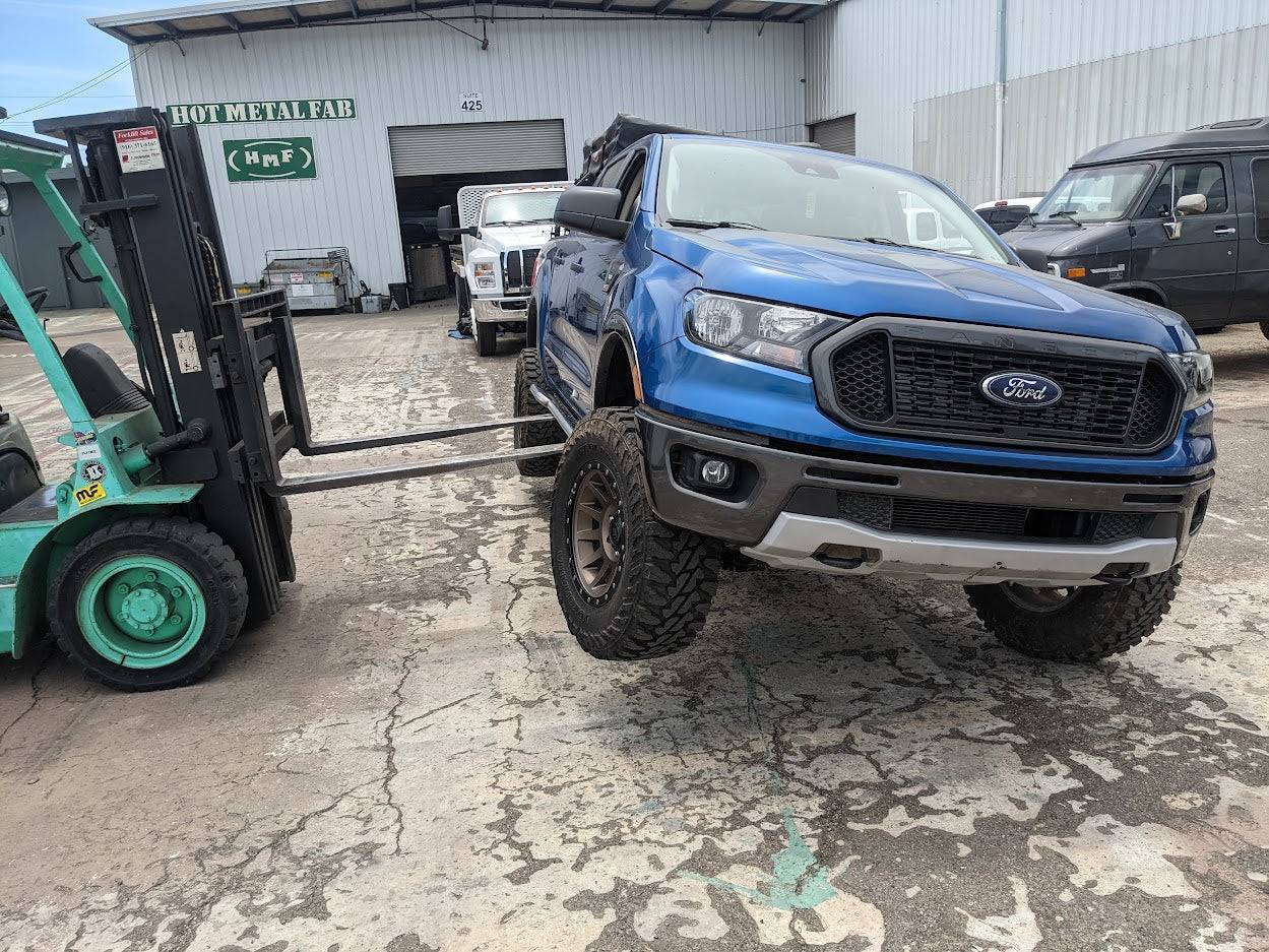 a blue pick up truck pulling a fork lift