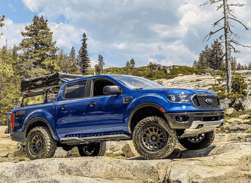 a blue truck parked on top of a rocky hill